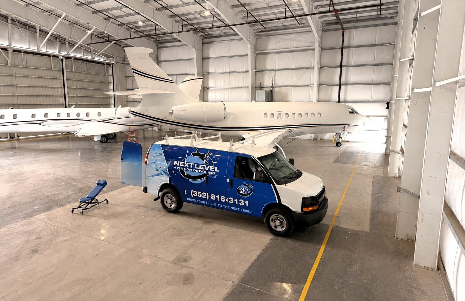 The Next Level van parked beside a private jet inside the hangar